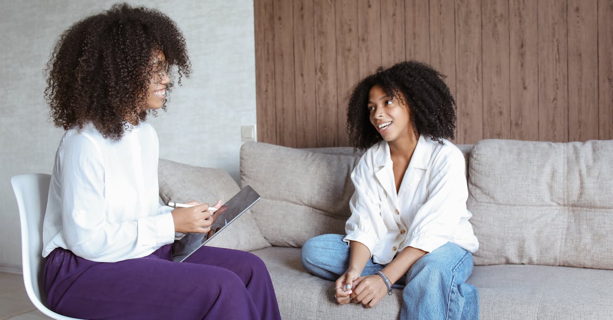 Two women in a friendly conversation on a sofa, showcasing a relaxed atmosphere.