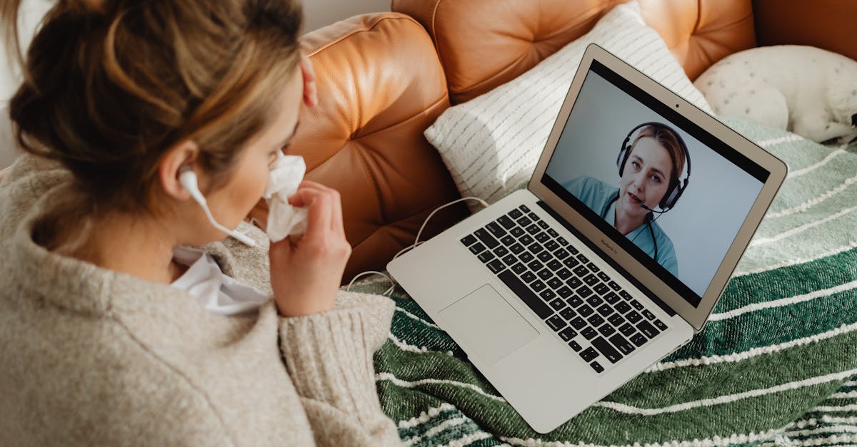 Woman having an online medical consultation on a laptop from her cozy sofa.