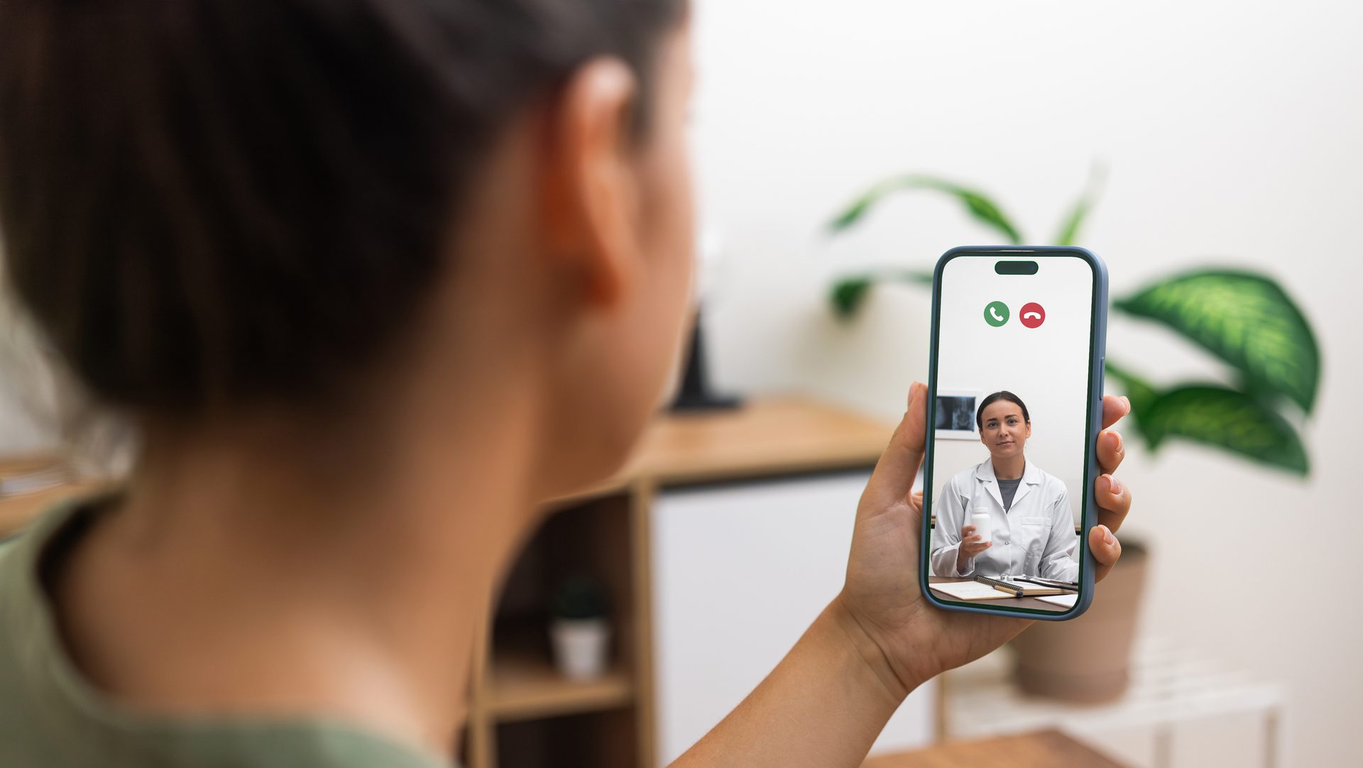 person receiving medical consultation through a video call with a smiling doctor on a smartphone, illustrating accessible telehealth services